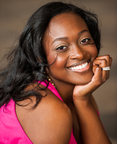 A woman smiling and holding her hand to the side.