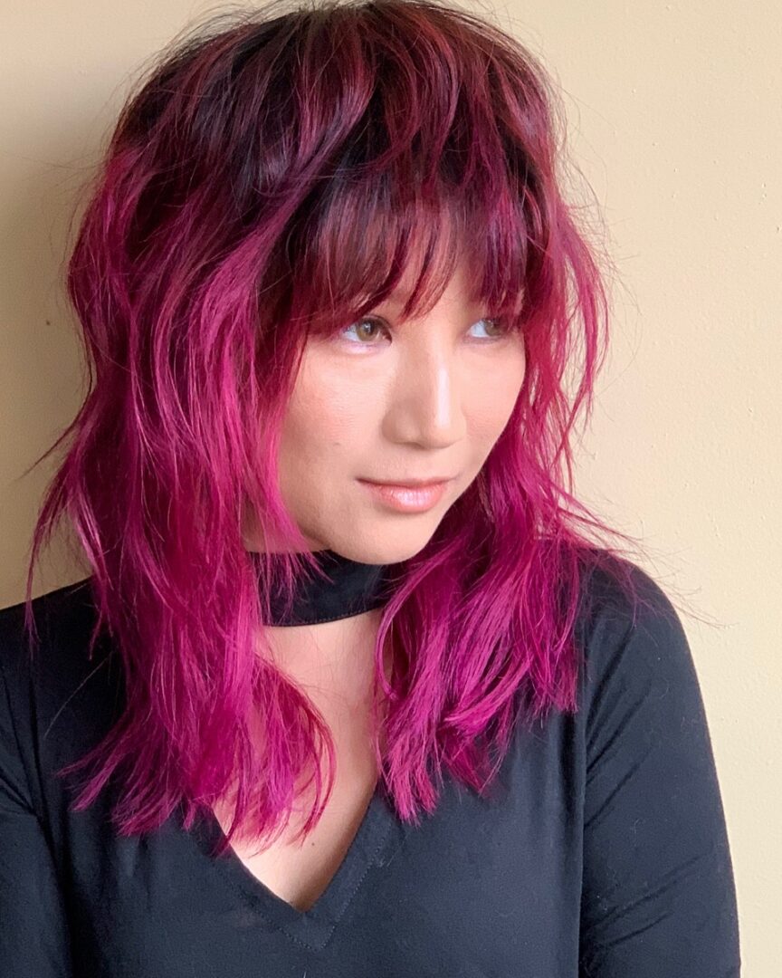 A woman with pink hair and black shirt